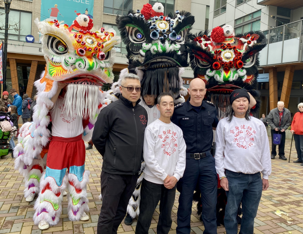 Officer standing with festival participants and Chinese New Year Lions.